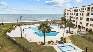 Un hotel con zona de piscina, vista al océano y un edificio con varios balcones.
