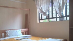 Un dormitorio con cama de madera, una ventana con cortinas, una mesita de noche y un estante en la pared.