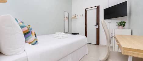 Ein Hotelzimmer mit Bett, Schreibtisch, Stuhl, Fernseher und einer Tür.