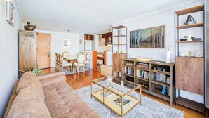 A living room with a sofa, coffee table, bookshelf, and dining area.