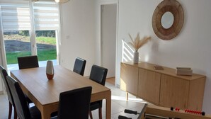 Un comedor con mesa y sillas, una mesa de fútbol de mesa, un espejo montado en la pared y una puerta que da a un espacio exterior.