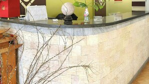 A hotel reception area with a stone counter, clocks on the wall, and a sign reading "HOANG". - Hoang Gia Hotel Cau Giay (Hanoi)