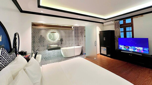 A modern hotel room with a large bed, a bathroom with a bathtub, a TV, and a large window. - Hoang Gia Hotel Cau Giay (Hanoi)