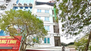 A hotel entrance with a red sign, potted plants, and motorcycles parked outside. - Hoang Gia Hotel Cau Giay (Hanoi)