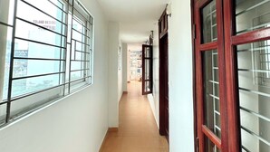 A corridor with white walls, a tiled floor, and windows with metal bars. - Hoang Gia Hotel Cau Giay (Hanoi)
