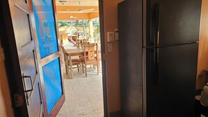 Una cocina con un refrigerador negro, una mesa de comedor de madera y sillas.