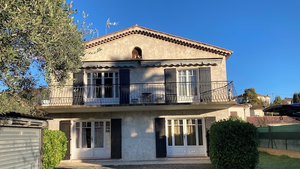 A two-story house with a balcony, a garage, and a well-maintained lawn.