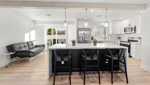 A modern kitchen with a central island, stainless steel appliances, and black bar stools. - Scottsdale Classic - Luxury Home w/ 5 Beds & Pool! (Scottsdale)