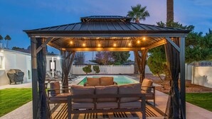 A covered outdoor seating area with a pool in the background. - Scottsdale Classic - Luxury Home w/ 5 Beds & Pool! (Scottsdale)