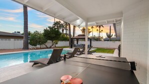 A poolside area with a table tennis table, lounge chairs, and a view of the pool and sunset. - Scottsdale Classic - Luxury Home w/ 5 Beds & Pool! (Scottsdale)