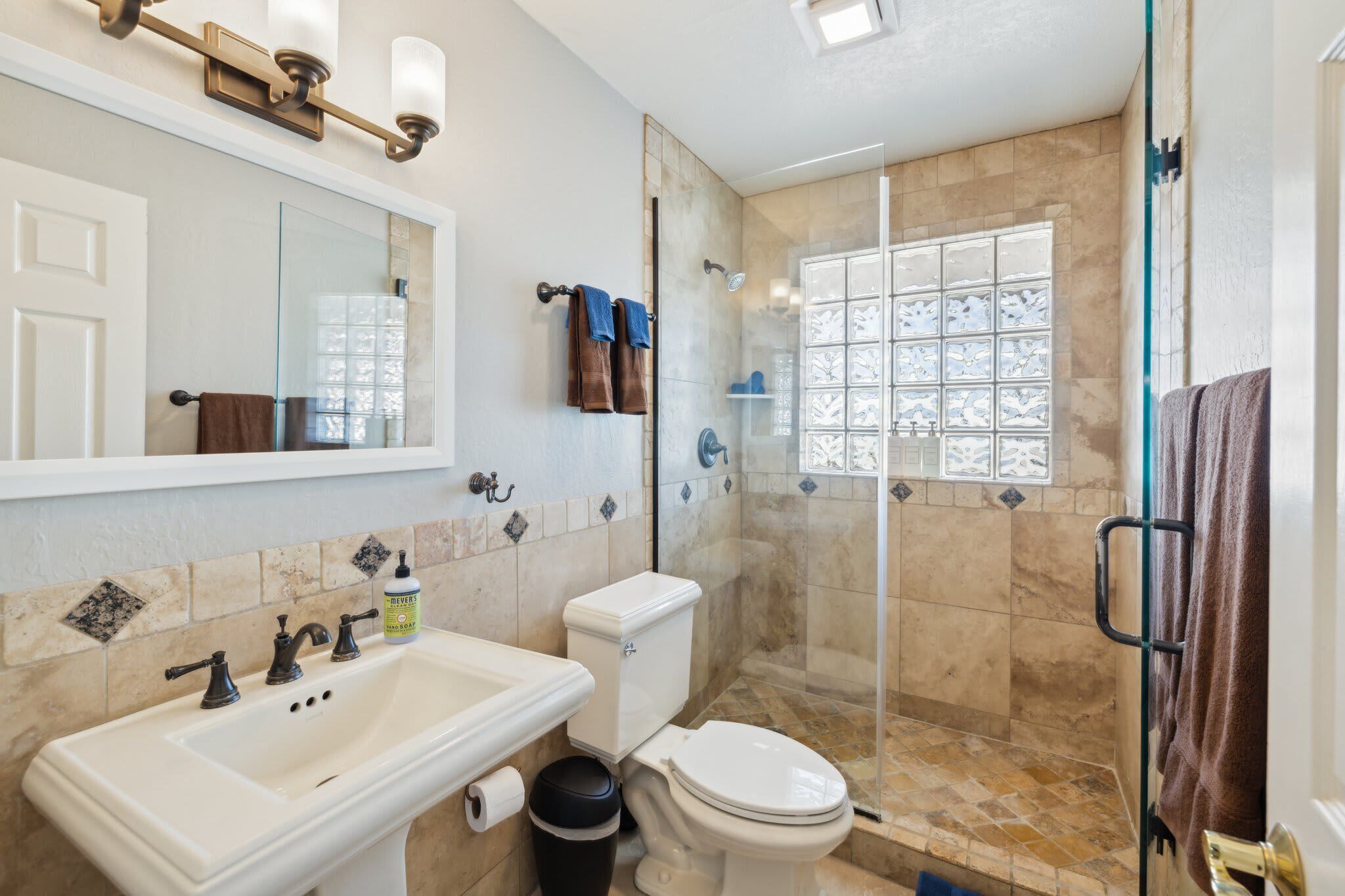 Un bagno con lavandino, WC e box doccia in vetro.