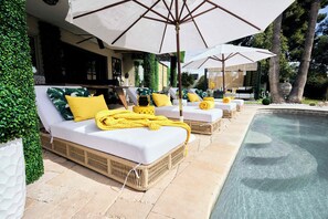 Zona de piscina amb gandules i ombrel·les.