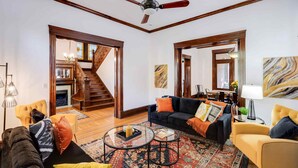 A spacious living room with a staircase, a fireplace, and a dining area.