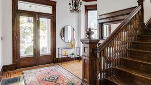 A grand entryway with a wooden staircase, a large mirror, and a chandelier.