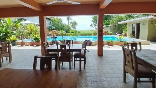 An outdoor patio area with a pool, wooden tables and chairs, and potted plants. - Casa Canadiense Cabina 1  of 5 BEACHFRONT PROPERTY (Chacarita)