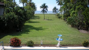 A swimming pool with a fountain, surrounded by a well-maintained lawn and palm trees, with a view of the ocean. - Casa Canadiense Cabina 1  of 5 BEACHFRONT PROPERTY (Chacarita)