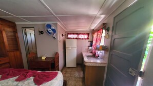 A compact room with a bed, a small table, a refrigerator, a sink, and a fan. - Casa Canadiense Cabina 1  of 5 BEACHFRONT PROPERTY (Chacarita)