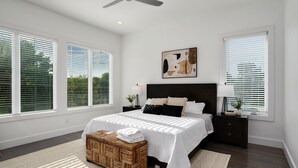 A bedroom with a large bed, a ceiling fan, and two bedside tables with lamps.