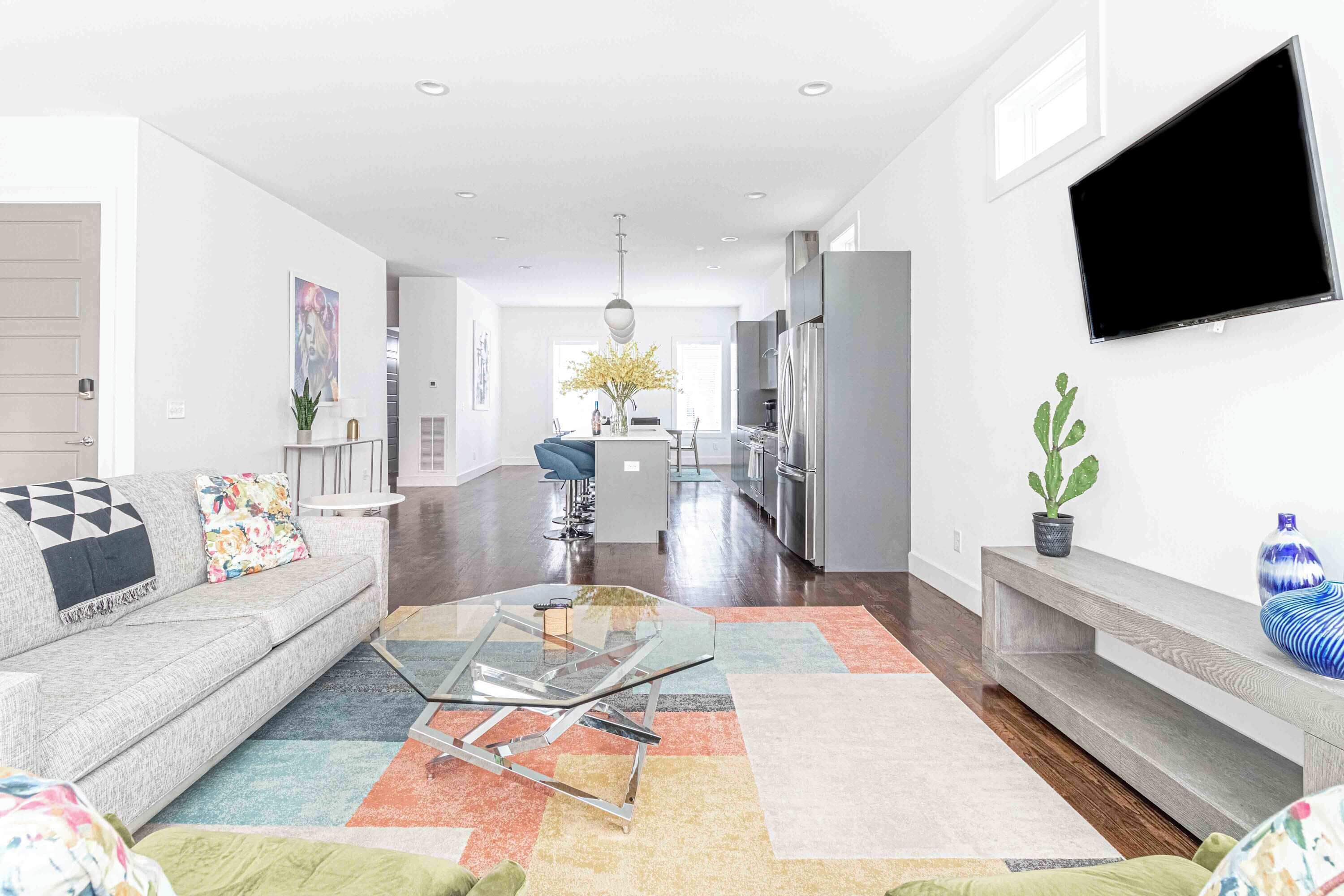 A modern living room with a sofa, coffee table, and a flat-screen TV mounted on the wall.