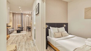 A modern hotel room with a large bed, a seating area with a sofa and a table, and a separate dining area. - Superb Apartment Invalides St Germain des Pres (Paris)