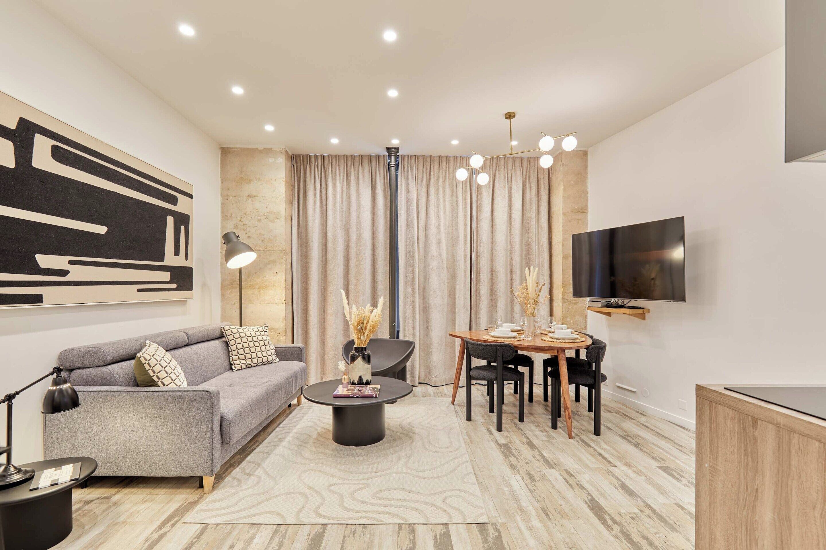 A modern living room with a sofa, coffee table, and dining area.