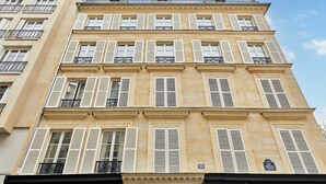 A multi-story building with white shutters, balconies, and a clear sky. - Superb Apartment Invalides St Germain des Pres (Paris)