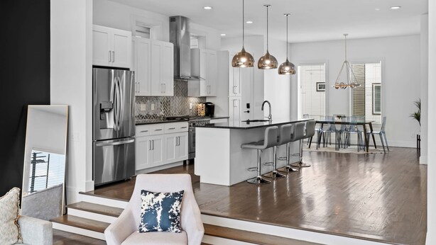 A modern kitchen with white cabinets, stainless steel appliances, and a central island with bar stools.