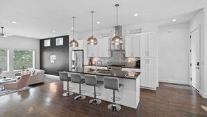 A modern kitchen with a central island, pendant lighting, and a seating area with bar stools.