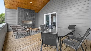 A covered outdoor patio with a wooden deck, a round table, and metal chairs.