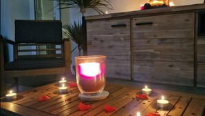 A wooden table with candles and a lit candle in a glass holder. - La Résidence Belle Créole (Quincy-Voisins)