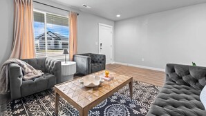 Ein Wohnzimmer mit einer Couch, Sesseln, einem Couchtisch und einem gemusterten Teppich.