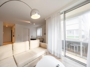 Ein modernes Wohnzimmer mit einer Couch, einem Esstisch und einer großen Schiebeglasdoor zu einem Außenbereich.