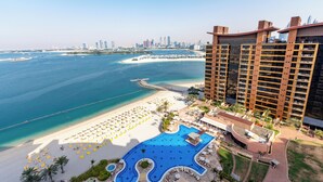 Un resort con una piscina grande, zona de playa y vistas del horizonte de la ciudad.