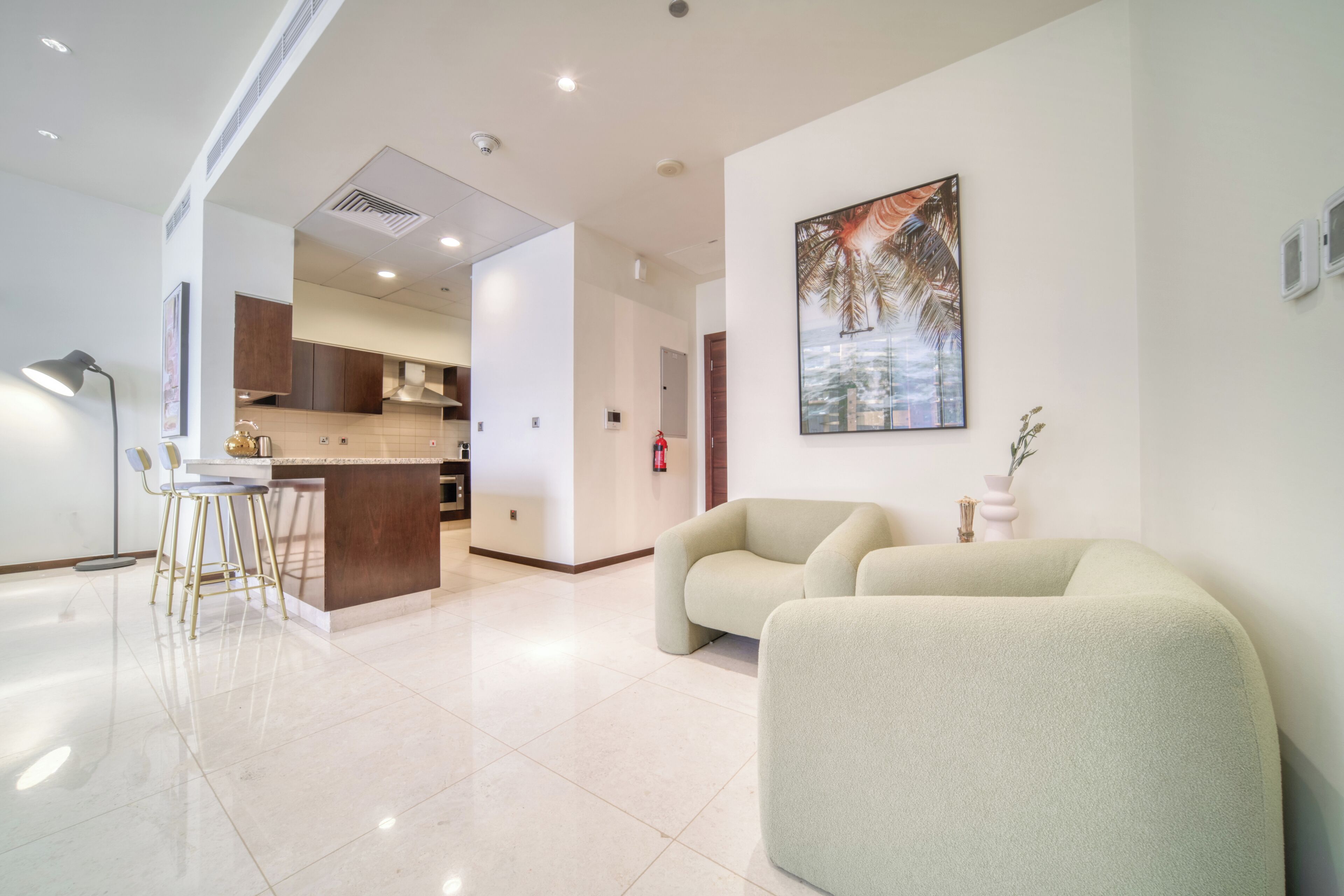 Una sala de estar moderna con un sofá, un comedor con barra y una cocina al fondo.
