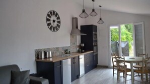 Une cuisine moderne dotée d’un îlot central, d’appareils électroménagers intégrés et de luminaires suspendus.