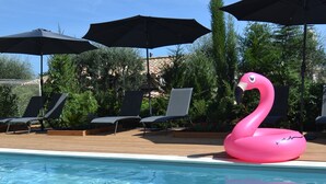 Une piscine à l’eau claire, entourée de chaises longues et de parasols.