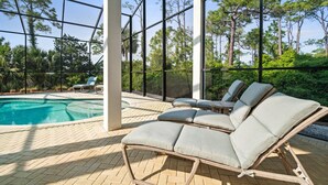 Un espace piscine intérieure avec des chaises longues et une vue sur les arbres à travers de grandes fenêtres.