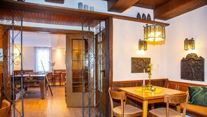 A dining area with a wooden table and chairs, a bench, and decorative wall sconces. - Winery Retreat in Germany With Wine Cellar (Sankt Goar)