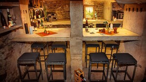 A rustic cellar bar with wooden stools, wine bottles, and a cozy ambiance. - Winery Retreat in Germany With Wine Cellar (Sankt Goar)