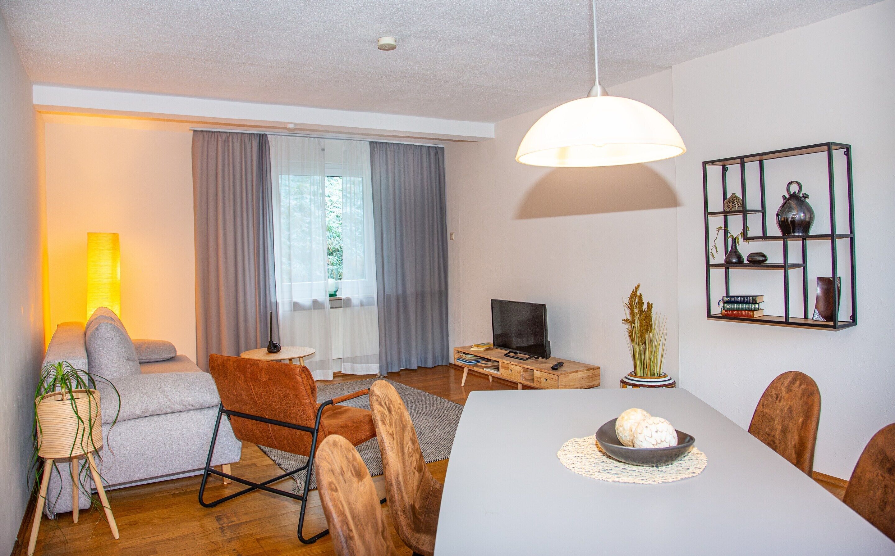 Un salon moderne comprenant une table à manger, un canapé, un téléviseur et une bibliothèque.