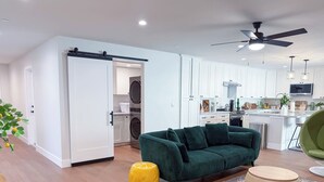 Ein modernes Wohnzimmer mit einem grünen Sofa, einem gelben Hocker und einem runden Holzschemel.