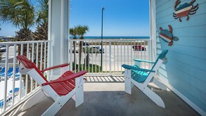 A balcony with two Adirondack chairs, a view of the beach, and a parking lot in the background. - Grand Caribbean 206 Fun in the Sun! (Orange Beach)