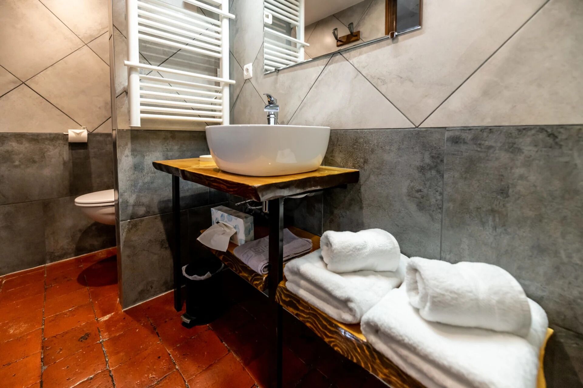 Un baño con un lavamanos blanco, un inodoro y un perchero para toallas.