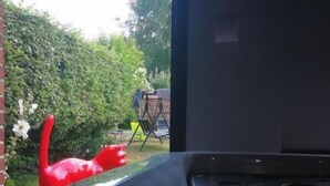 Een jacuzzi met waterstralen, een rode sculptuur en uitzicht op de tuin.
