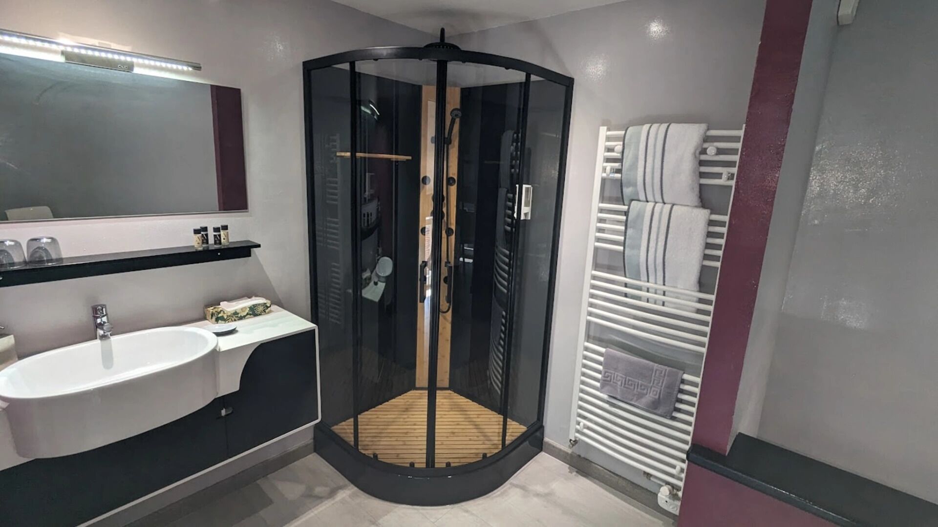 A modern bathroom with a glass-enclosed shower, a sink, and a towel rack.