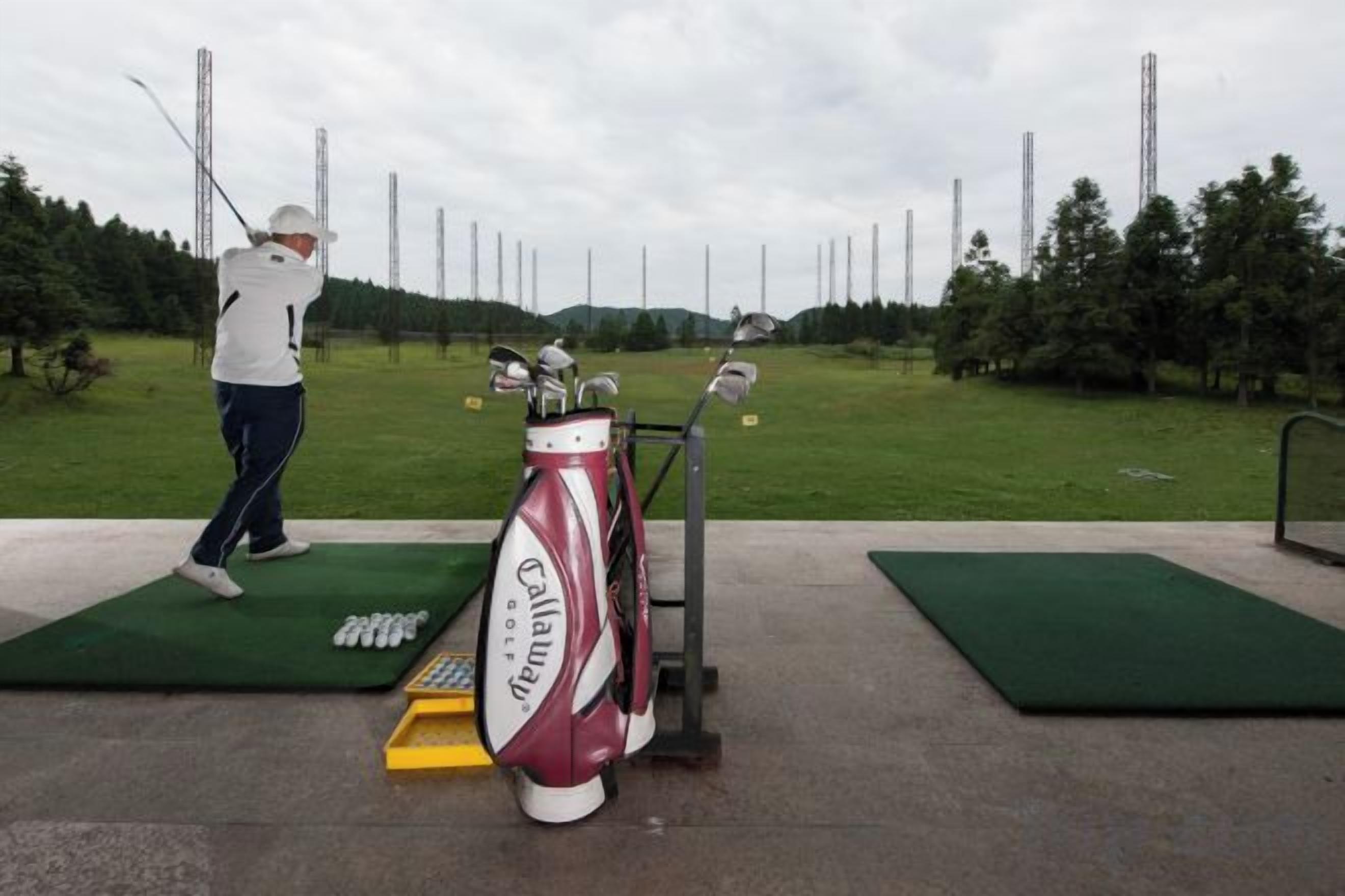 A golf course with a putting green, a golf bag, and a golfer in action.
