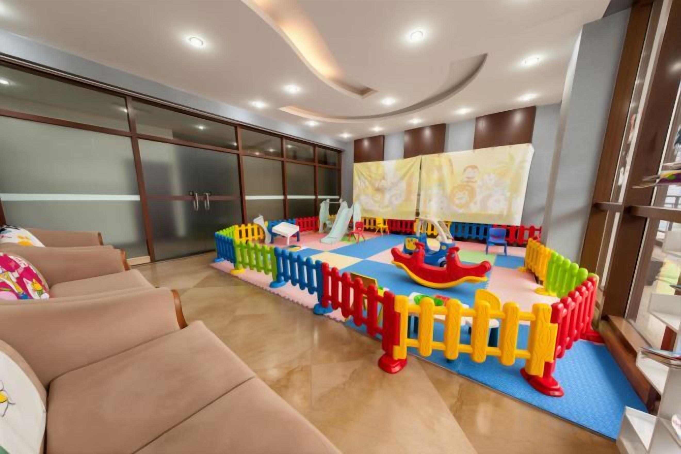 A play area with colorful play structures and a slide, surrounded by seating.