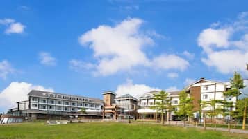 A hotel with multiple buildings, a grassy area in front, and a clear sky.