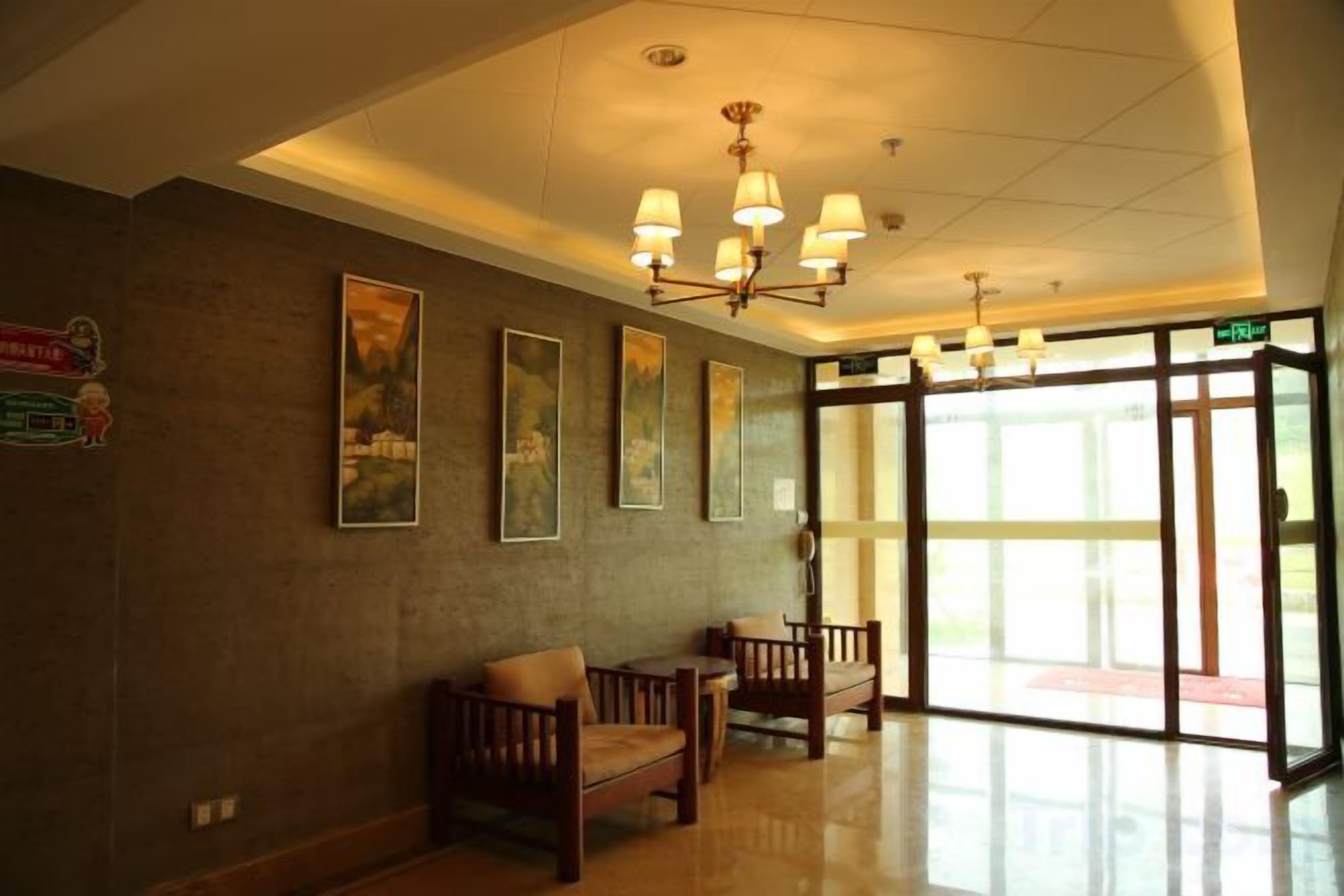A hotel lobby with a reception desk, seating area, and large windows.