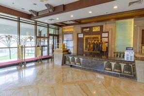 A hotel reception area with a marble floor, a reception desk, a coat rack, and a window with a view. - Xinhua Hotel Fairy Mountain (Chongqing)